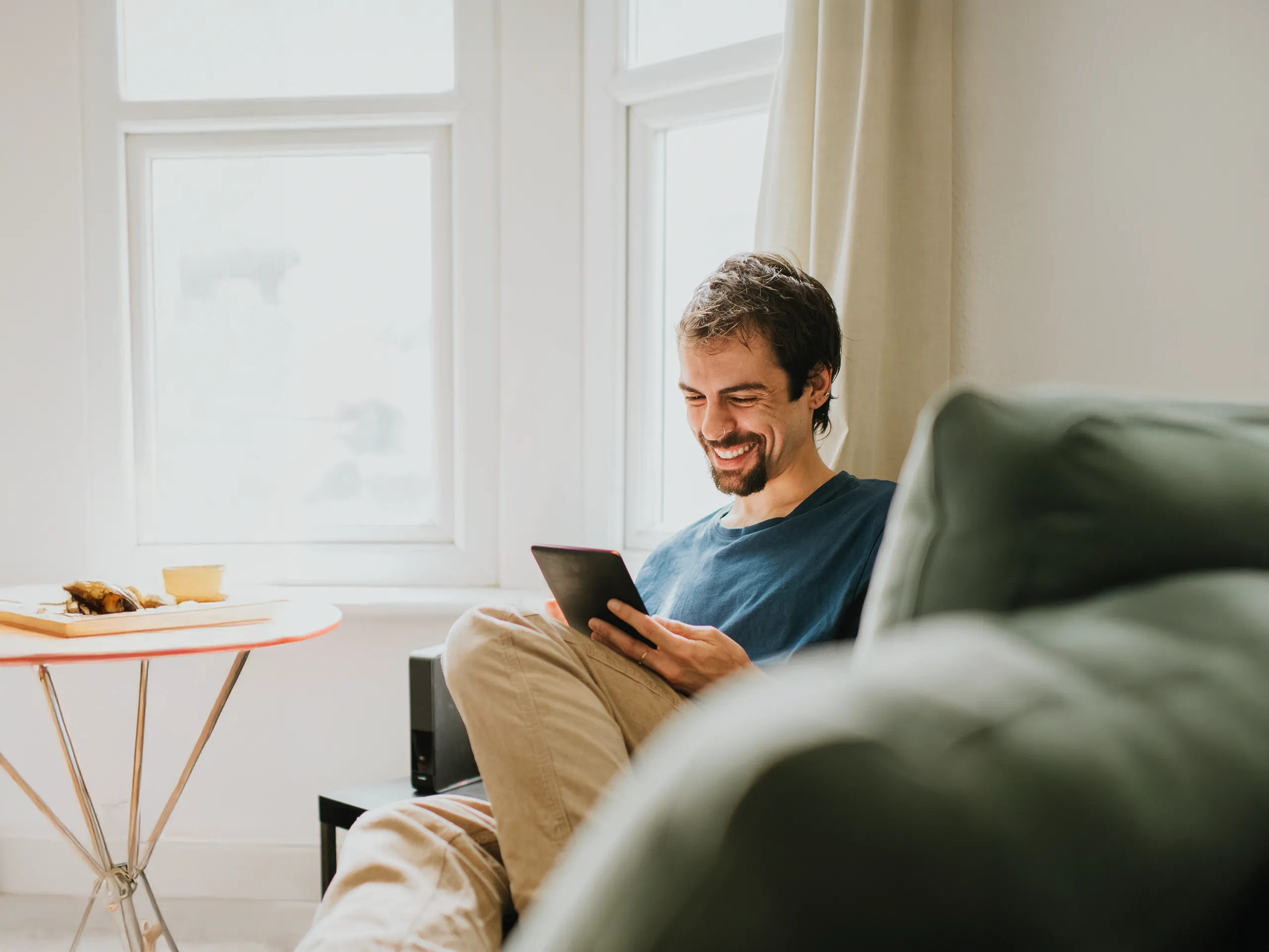 Un home llegint relaxat en una tauleta a la sala d'estar.