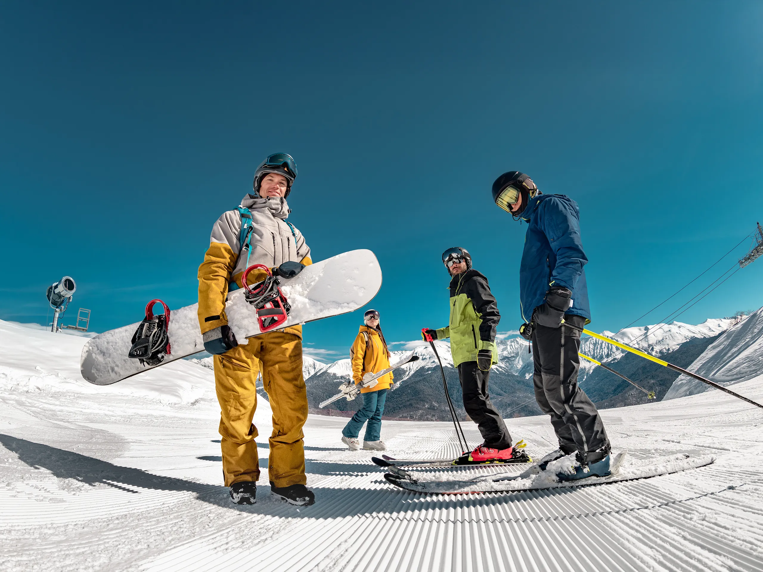 Group of winter sports enthusiasts with snowboards and skis on a snowy slope.